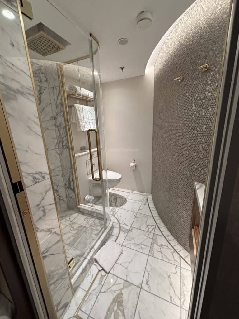 Luxurious bathroom in the Concierge Tower Suite on the Disney Destiny with marble flooring, a glass shower, and modern amenities.
