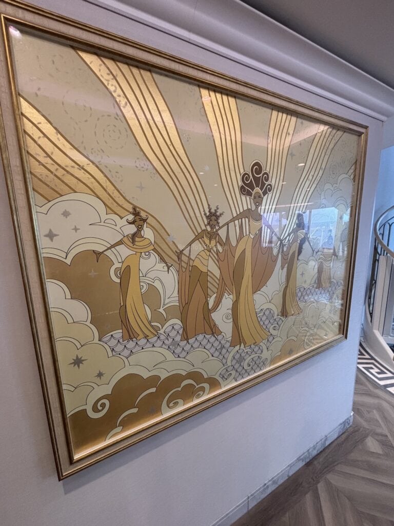 A decorative wall art piece featuring elegant figures in gold and brown tones, surrounded by cloud motifs, displayed in a cruise ship hallway.
