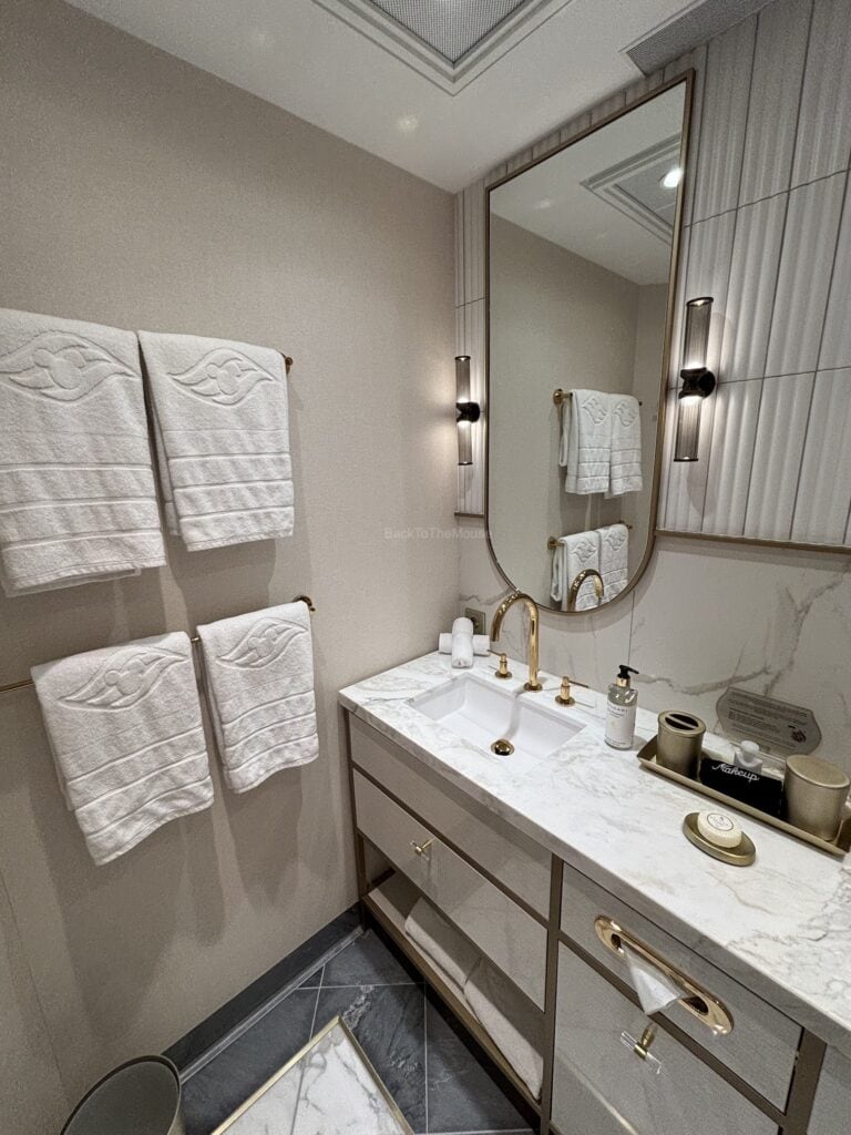 Luxurious bathroom featuring a double sink vanity with marble countertops, elegant fixtures, fluffy white towels, and a large mirror.