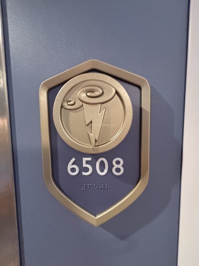 Room number sign for stateroom 6508 on the Disney Destiny, featuring a decorative design and braille.