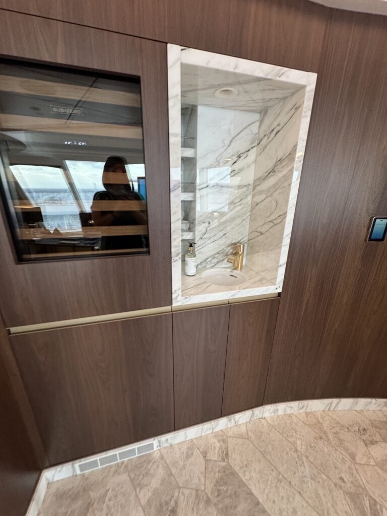 Interior view of a luxurious bathroom area in Stateroom 14000 on the Disney Destiny, featuring marble accents and modern design elements.