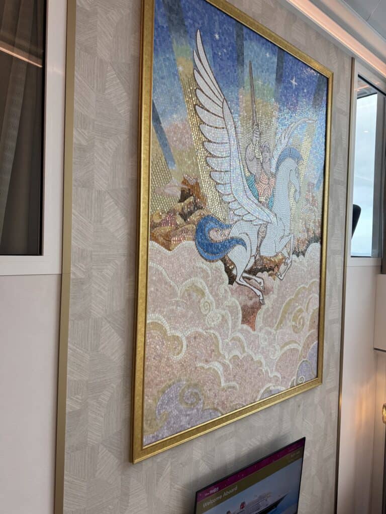 A decorative mosaic artwork featuring a winged horse soaring through clouds, with a knight holding a sword in the background, displayed in a luxurious stateroom.