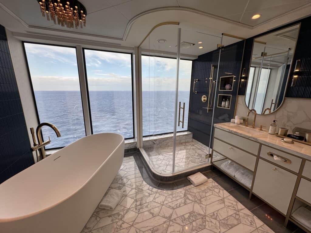 Luxurious bathroom with a freestanding bathtub, large windows overlooking the ocean, and modern fixtures.
