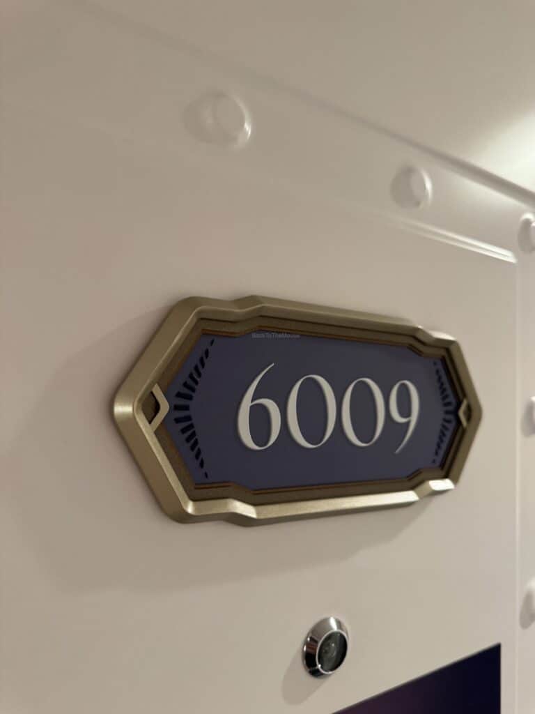 Door plaque of stateroom 6009 on the Disney cruise ship, showcasing the room number on a decorative background.